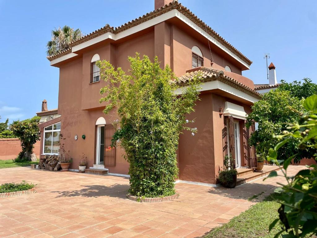 una gran casa marrón con un árbol delante en Chalet Oasis, en Novo Sancti Petri