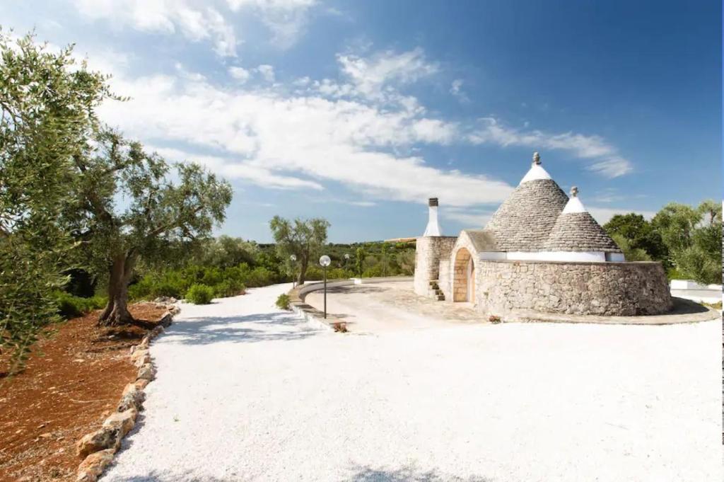 a stone building with a roof on a dirt road at Trullo Ada in Ceglie Messapica