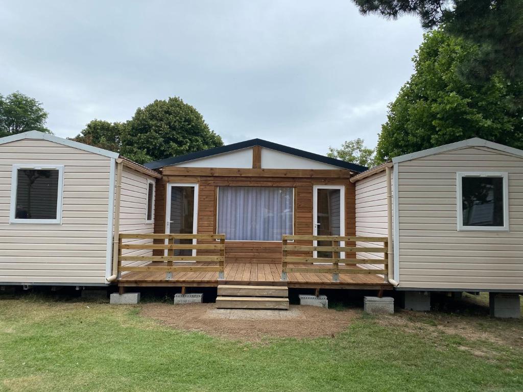 a manufactured home with a deck and a house at Camping Le Royan in Royan