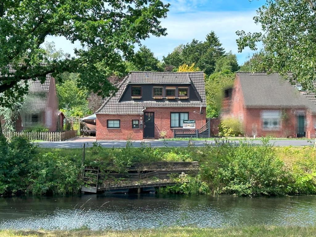 una casa con un puente sobre un río en Ferienwohnung No 1 am Golfplatz, en Wiesmoor