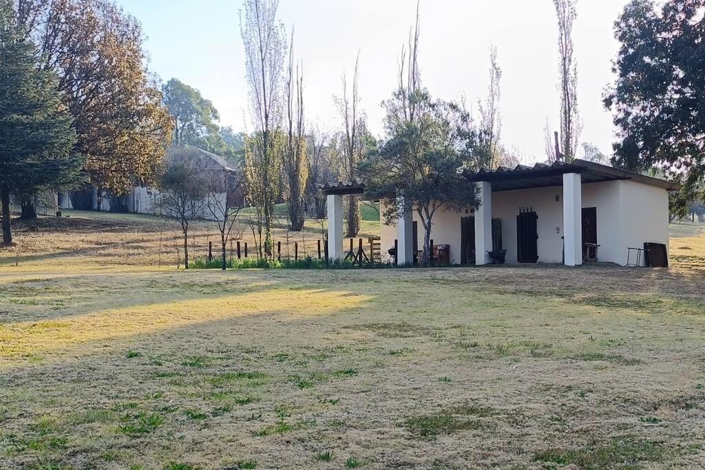 a small white building in a field with a yard at The Stables in Roodepoort