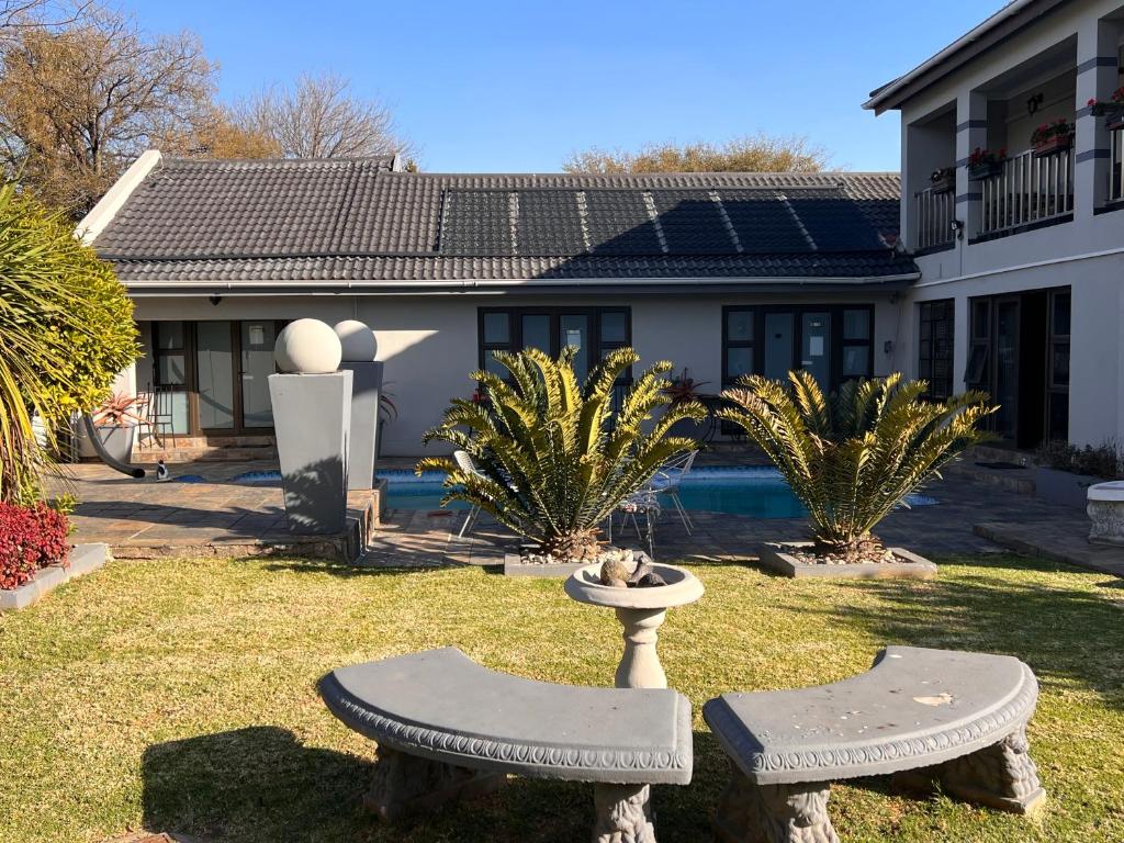 a house with two stone benches in a yard at 2 Op Terblanche Guesthouse in Boksburg