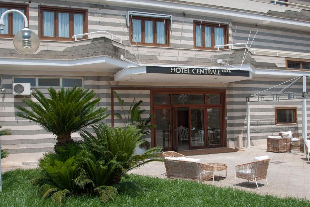 a hotel building with a table and chairs in front of it at Hotel Centrale in Sabaudia