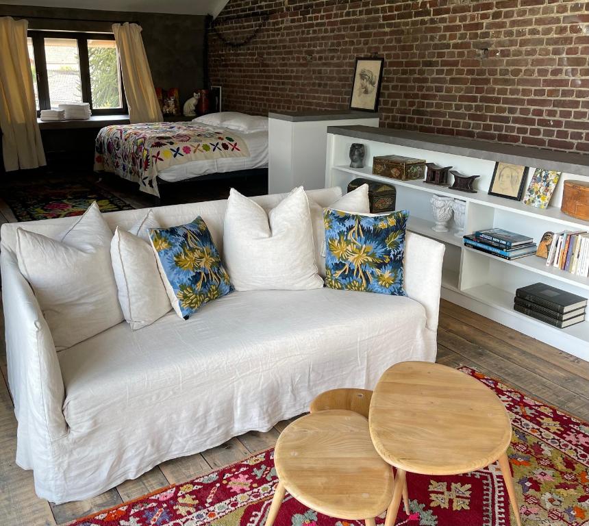 una sala de estar con un sofá blanco y mesas. en Lofts L'Écluse, parking gratuit, en Saint-Valery-sur-Somme