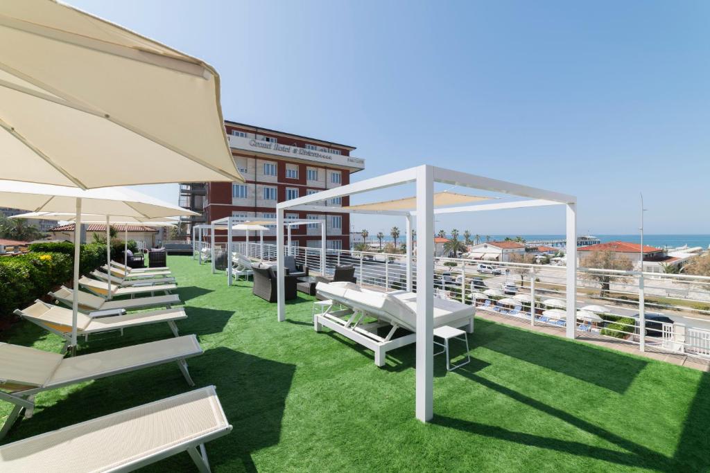 a row of white chairs and umbrellas on a roof at Grand Hotel & Riviera in Lido di Camaiore