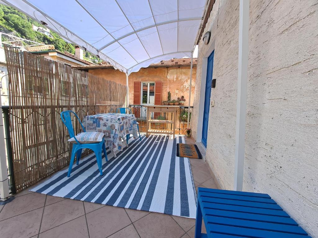 a patio with a table and chairs on a blue floor at Immobillario - Maison Felix in Gravedona