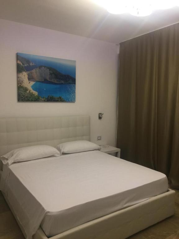 ポルト・チェザーレオにあるGaribaldi Roomsの白いベッド1台付きのベッドルーム1室(壁に絵画付)