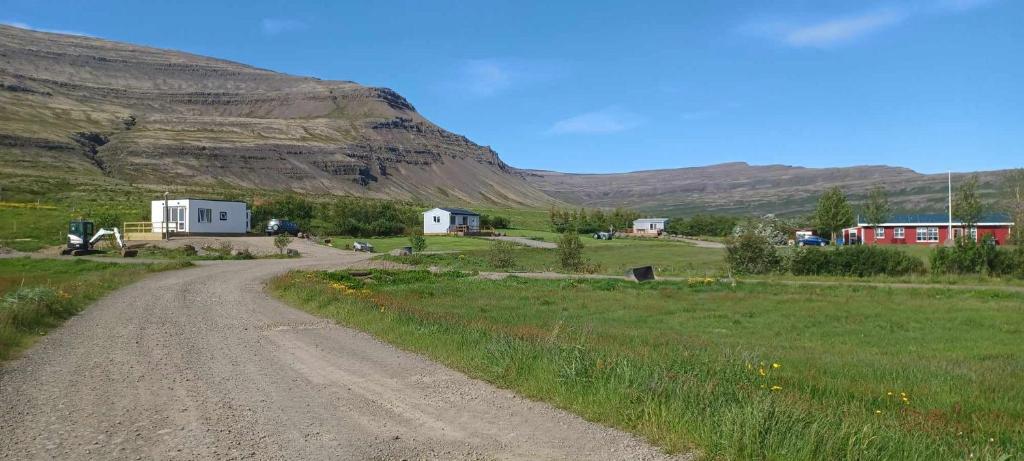 a dirt road in a field next to a mountain at Hagi 2 Road 62 in Patreksfjörður