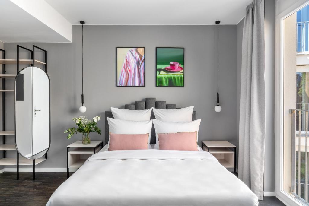 numa I Boxer Rooms and Apartments في برلين: غرفة نوم مع سرير أبيض كبير مع وسائد وردية