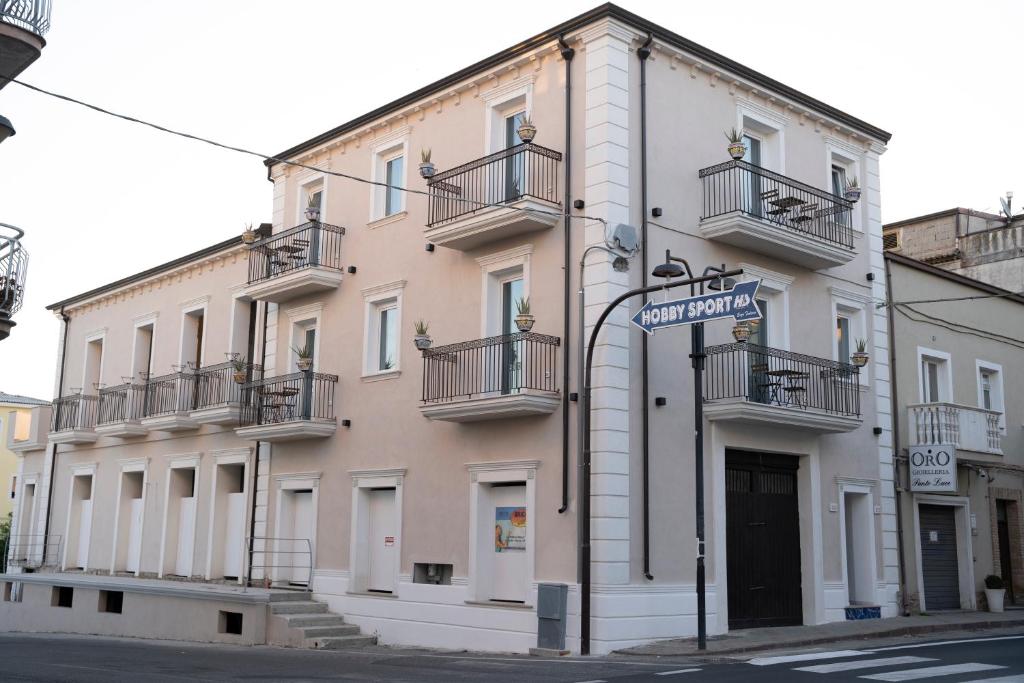 ein großes weißes Gebäude mit Balkonen und einem Straßenschild in der Unterkunft Antico Palazzo del Corso in Crosia