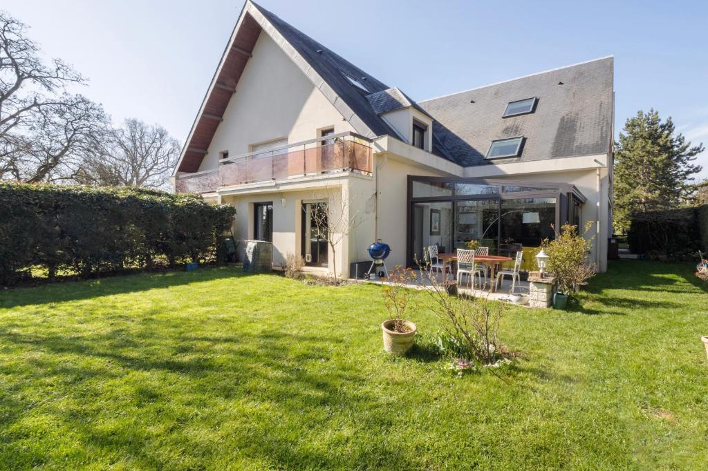 een huis met een grasveld met een huis bij Beau 4 pièces avec grand jardin et tennis in Jouy-en-Josas