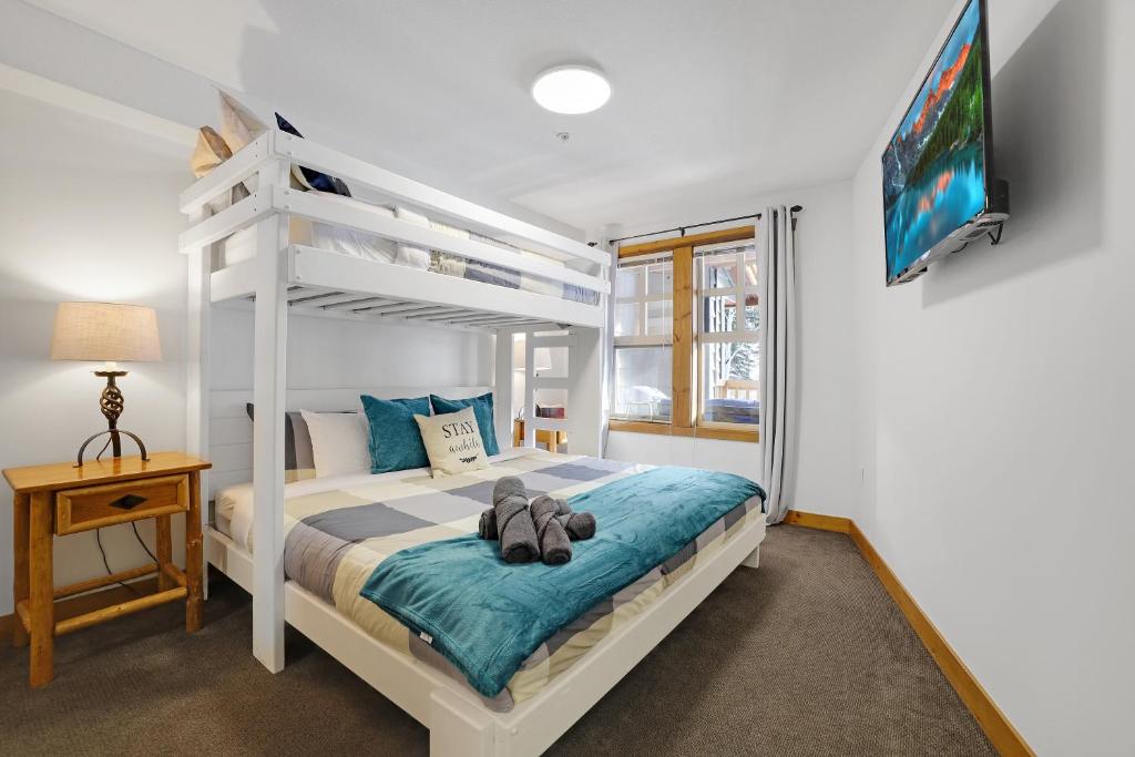 ein Schlafzimmer mit einem weißen Etagenbett und einem TV in der Unterkunft Perfect Ski or Bike in-out Hot Tub Pool in Panorama