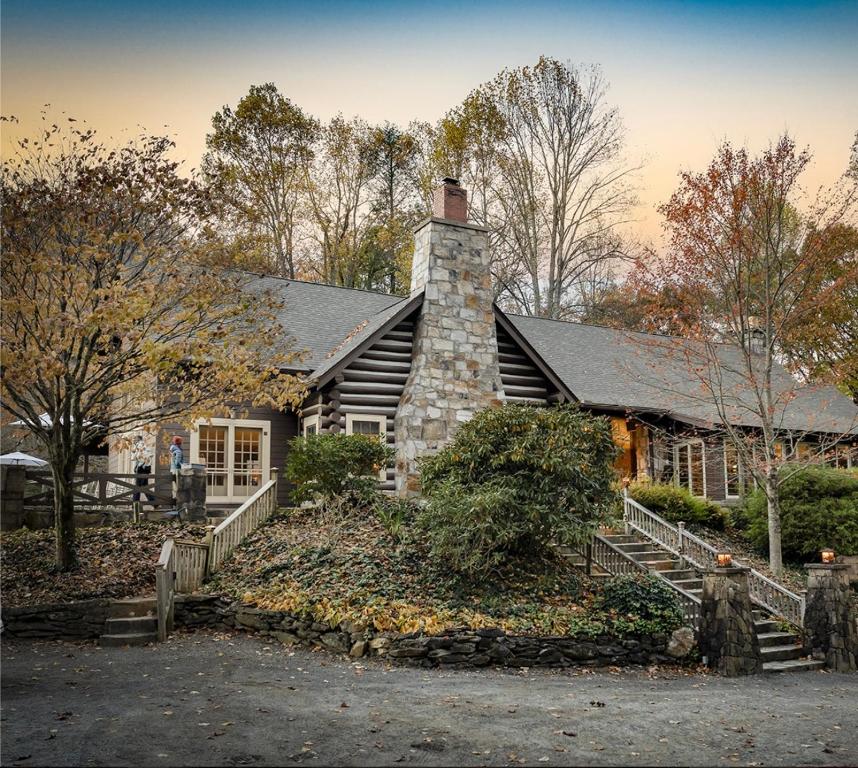 a house with a stone chimney and stairs to it at Snowbird Mountain Lodge in Robbinsville