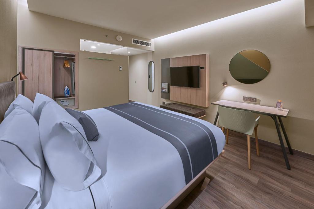 a hotel room with a large bed and a television at City Express Plus by Marriott Tijuana in Tijuana