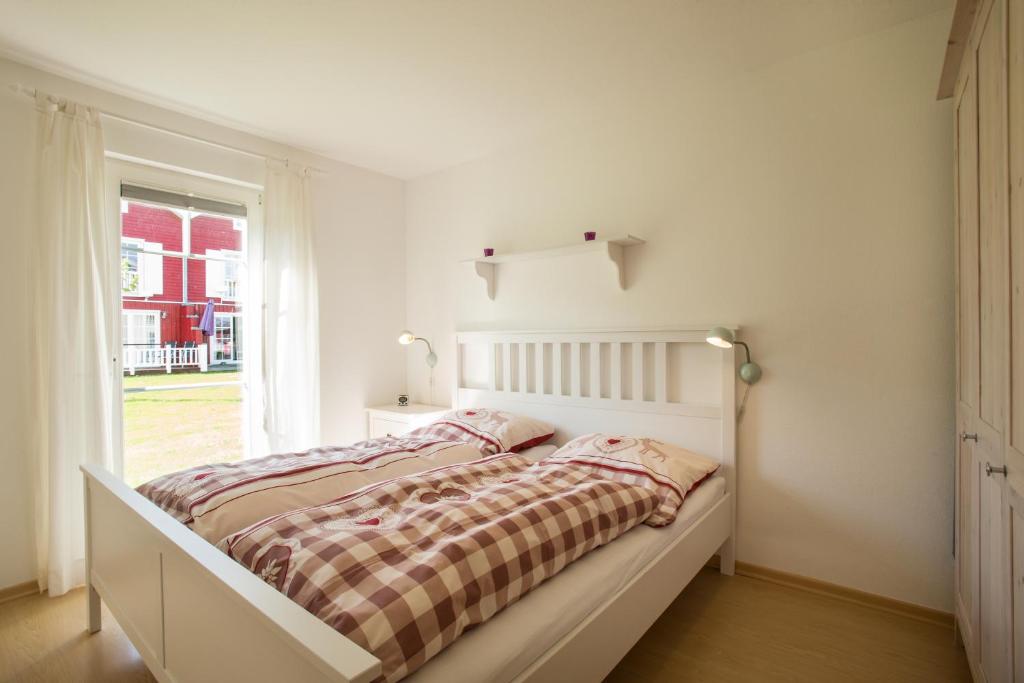 - une chambre blanche avec un lit et une fenêtre dans l'établissement Ferienwohnung Strandnest Sierksdorf, à Sierksdorf