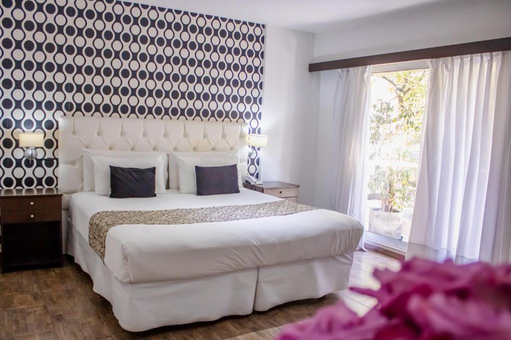 una camera da letto con un grande letto bianco e una grande finestra di Ker Belgrano Hotel a Buenos Aires