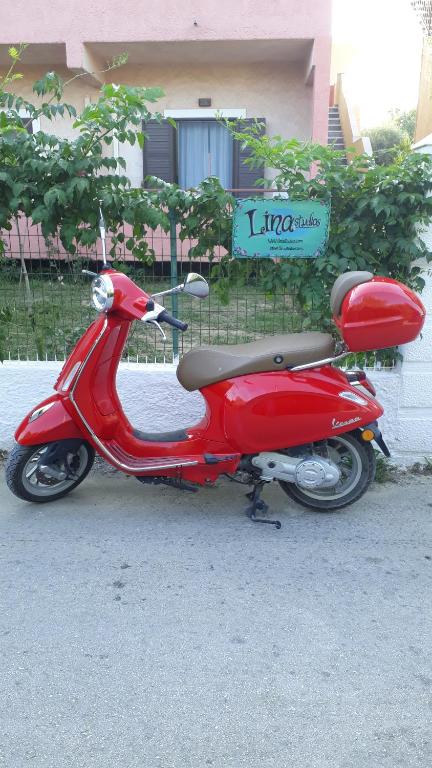 czerwony skuter zaparkowany przy ulicy w obiekcie lina studios w mieście Mesongi