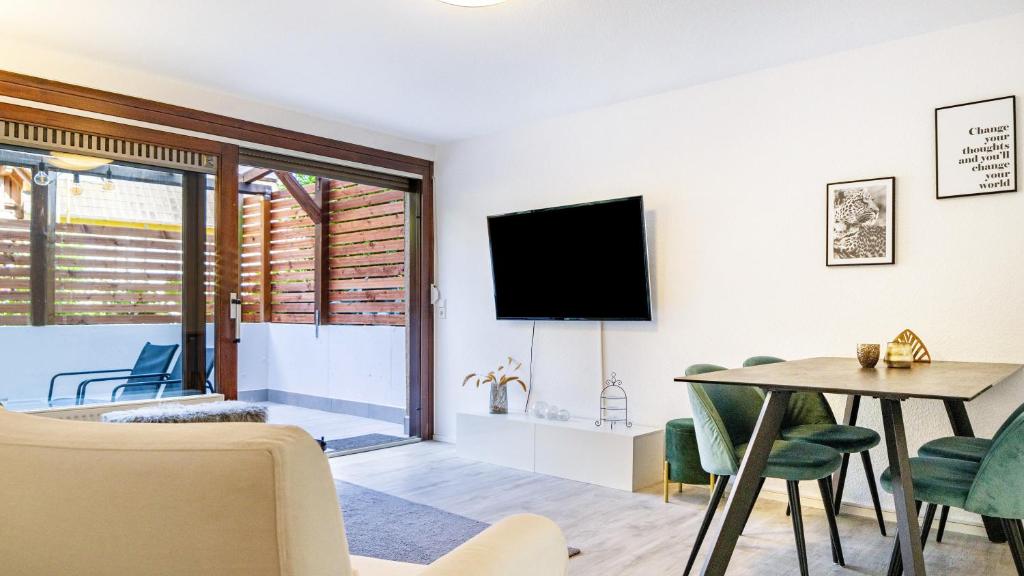 a living room with a tv and a table and chairs at Becks schöne Ferienwohnung in Vogtsburg