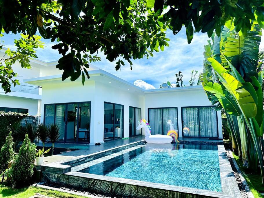 a villa with a swimming pool in front of a house at Villa có hồ bơi riêng tại Lang Phuoc Hai 