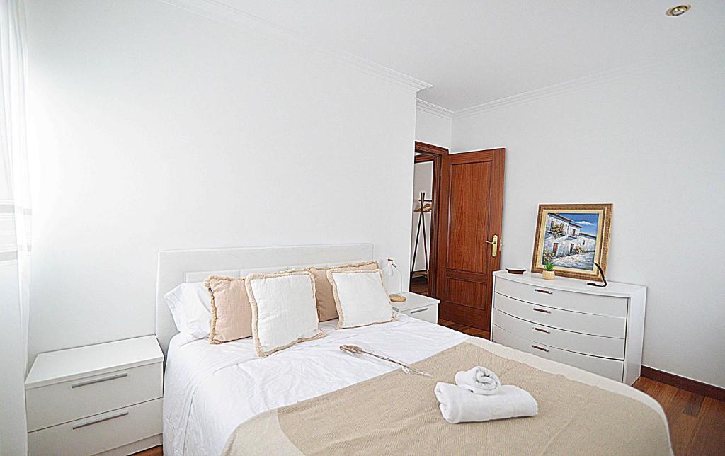 een witte slaapkamer met een bed en een dressoir bij Precioso apartamento en Santander in Santander