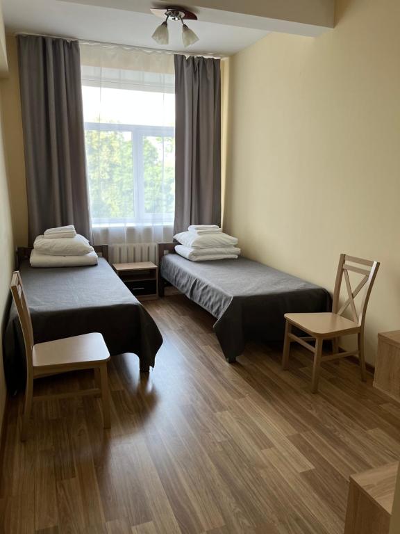 Duas camas num quarto com uma janela e uma cadeira em Guesthouse Zarasai em Zarasai