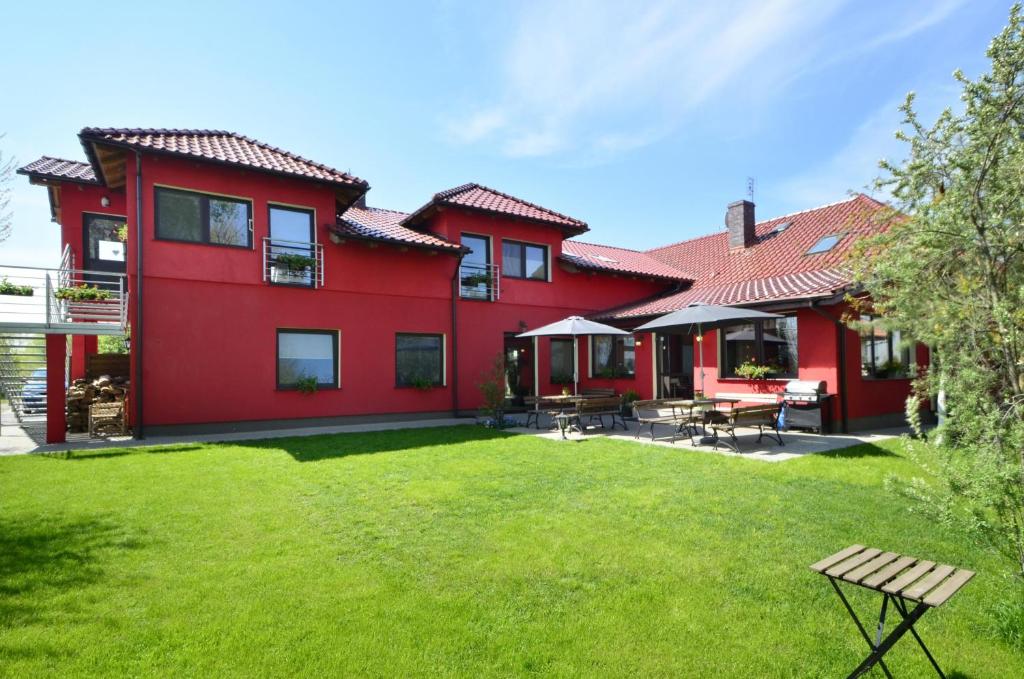 une maison rouge avec une pelouse devant elle dans l'établissement Pensjonat Paskal, à Czerlejno