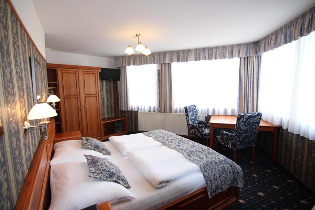 a hotel room with a bed and a desk and windows at Old Prague Hotel in Prague