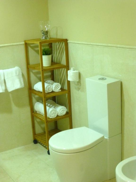 a bathroom with a toilet and a shelf with towels at Casa Valdevaqueros in Tarifa
