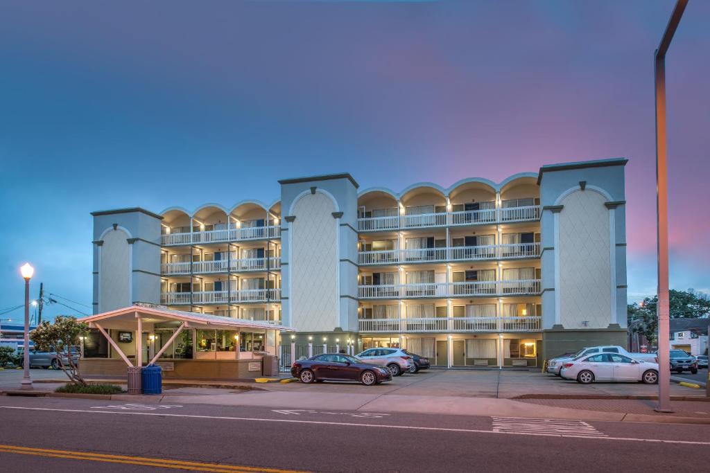 een groot gebouw met auto's geparkeerd op een parkeerplaats bij SureStay Hotel by Best Western Virginia Beach Royal Clipper in Virginia Beach
