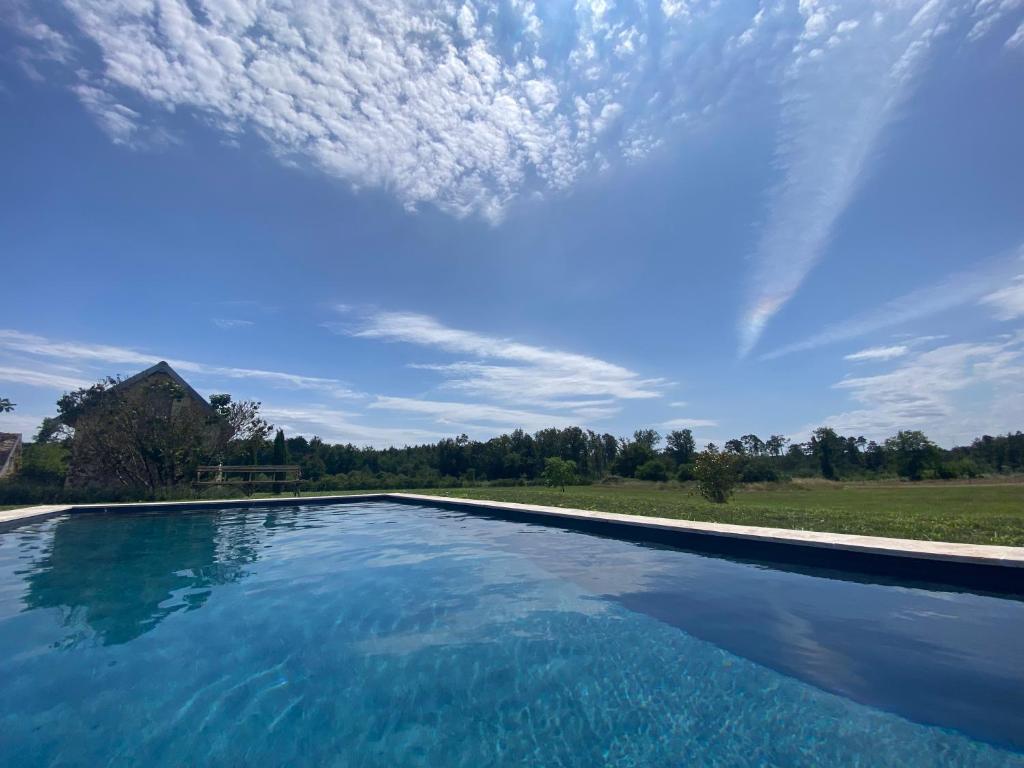 una piscina con cielo azul y nubes en La Michellière à Continvoir, en Continvoir