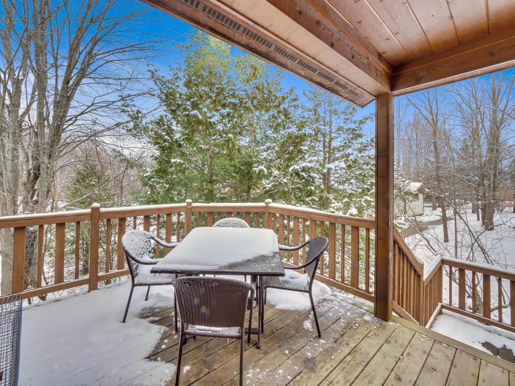 a table and chairs on a deck with snow on it at 678 Disciples Village Unit in Boyne Falls