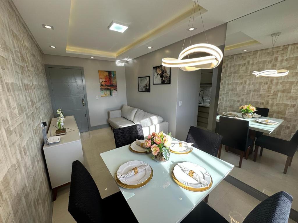 comedor y sala de estar con mesa y sillas en Lindo Apartamento Inteiro Proximo ao Centro de Criciuma, en Criciúma