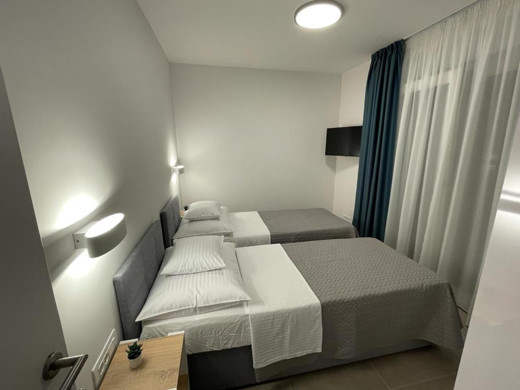 2 Betten in einem kleinen Hotelzimmer mit einem Schreibtisch und einem Bett in der Unterkunft Markioli Residence in Sevid