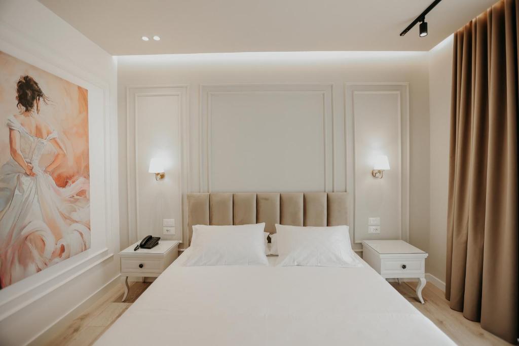 Un dormitorio con una gran cama blanca y una pintura en Seaside Hotel, en Vlorë