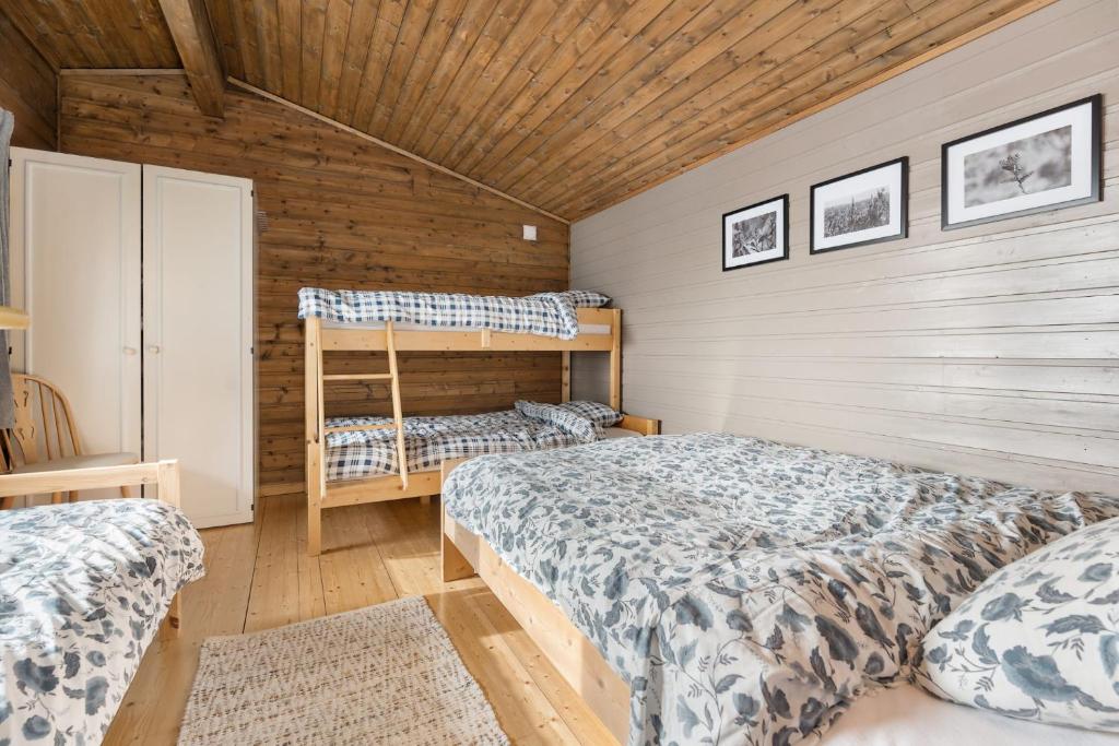 a bedroom with two beds and a wooden wall at Lyngebu. Nice family cabin with sea view. in Lyngdal