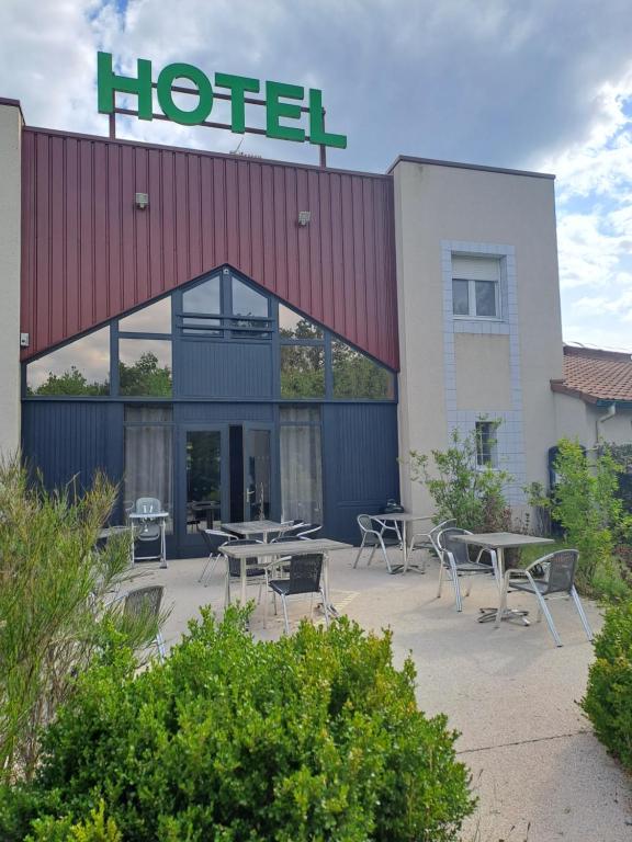 a hotel with tables and chairs in front of it at Hôtel Le Grand Chêne in Gièvres