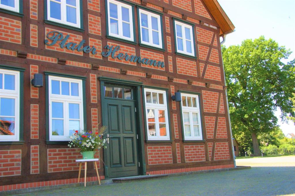 ein rotes Backsteingebäude mit grüner Tür und Blumen in der Unterkunft Plater Hermann in Lüchow