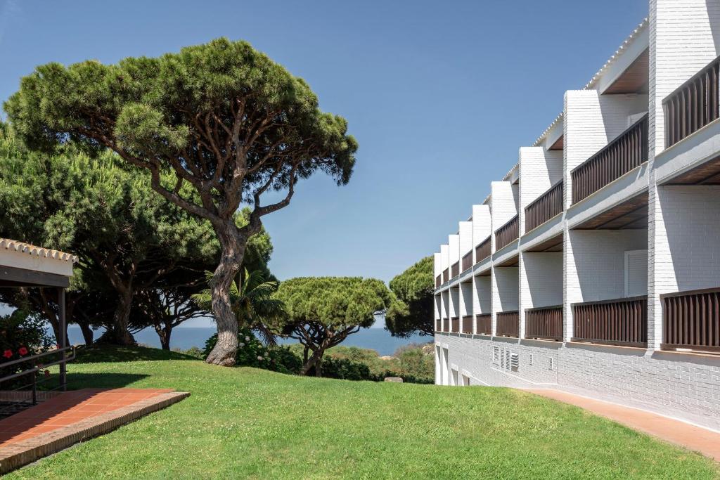 a building with trees and grass in front of it at Parador de Mazagón in Mazagón