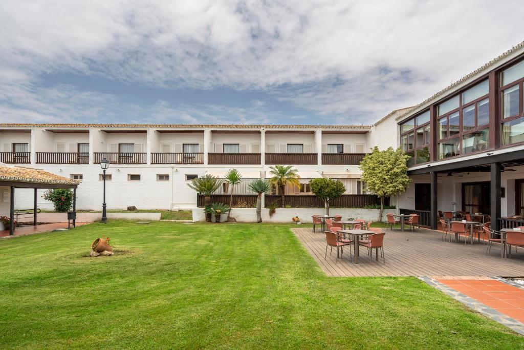 a courtyard of a building with a dog sitting on the grass at Parador de Mazagón in Mazagón