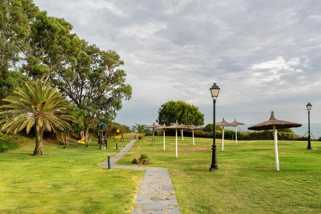a park with umbrellas and a path in the grass at Parador de Mazagón in Mazagón