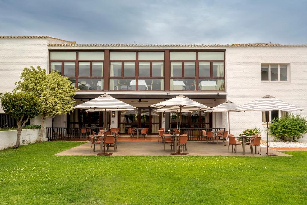 a building with tables and chairs and umbrellas at Parador de Mazagón in Mazagón