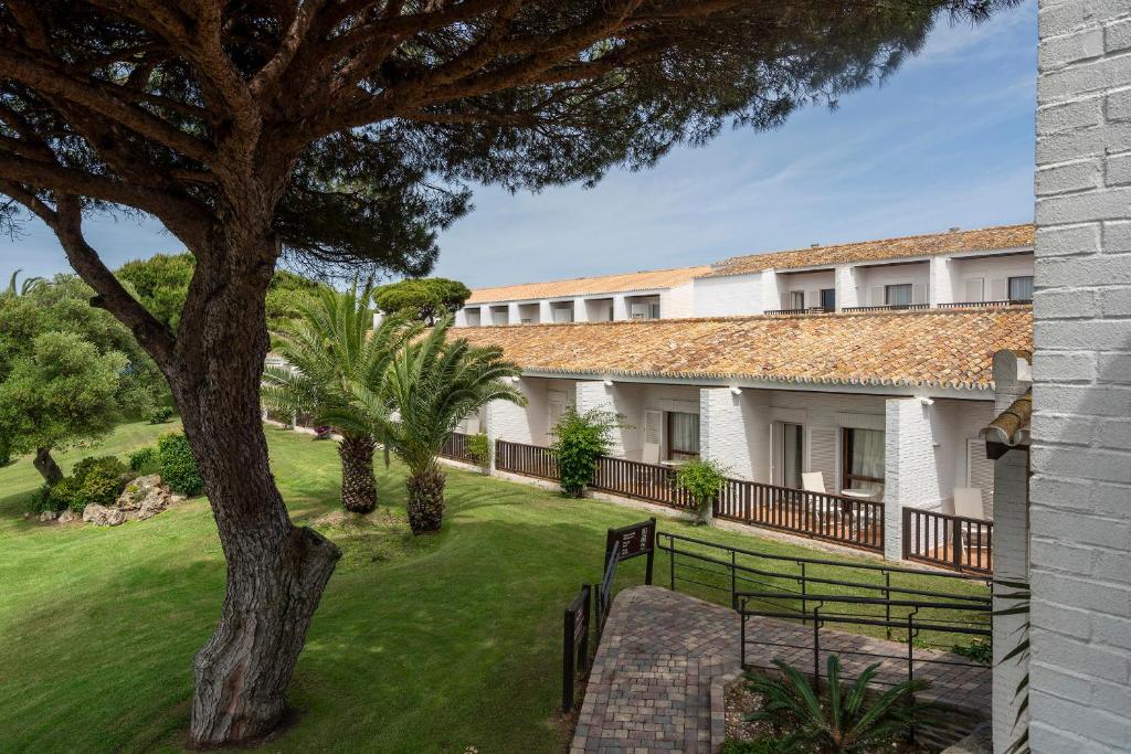 an exterior view of a building with a tree at Parador de Mazagón in Mazagón