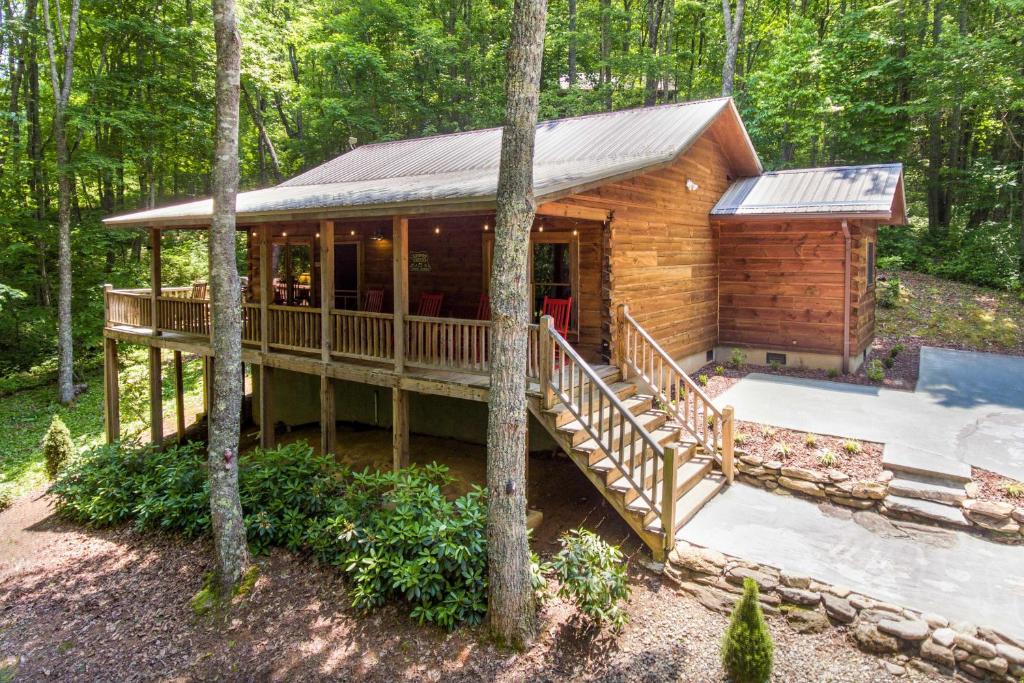 eine Blockhütte im Wald mit einer Terrasse und einem Pool in der Unterkunft Great Smoky Mountains Cabin near Cashiers, NC! in Glenville