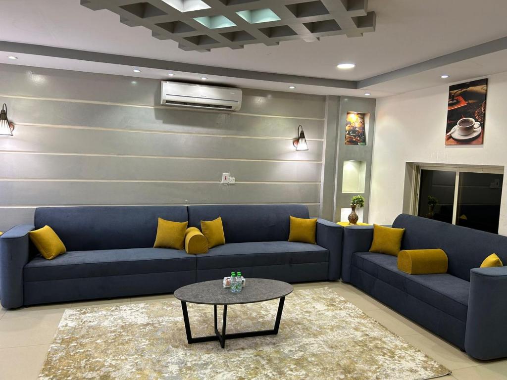 a living room with a blue couch and yellow pillows at ليلتنا1 in Hail