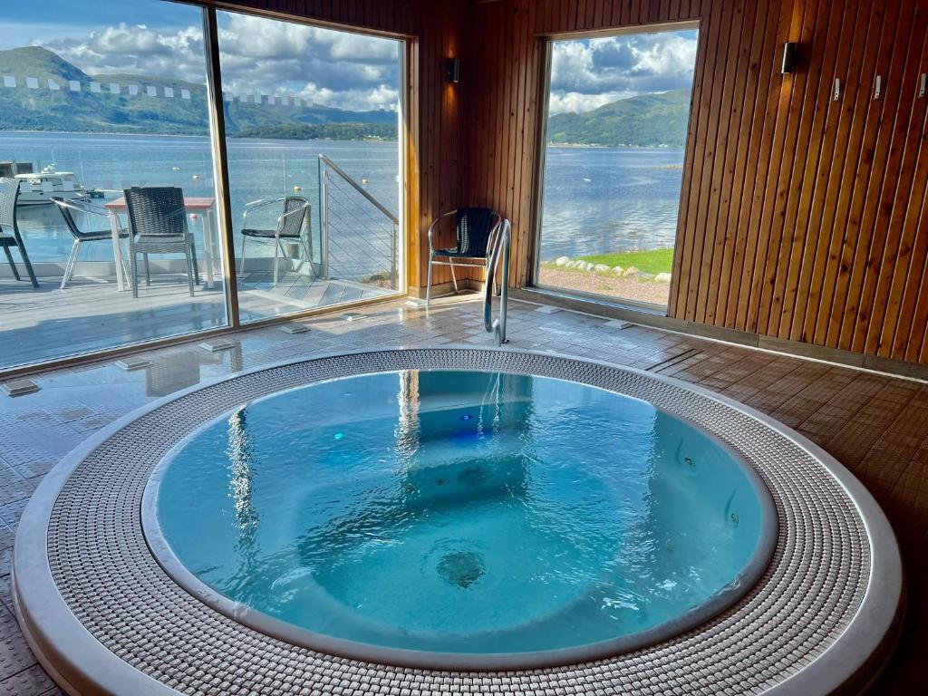 a hot tub in a room with a view of the water at Holly Tree Hotel, Swimming Pool & Hot Tub in Glencoe