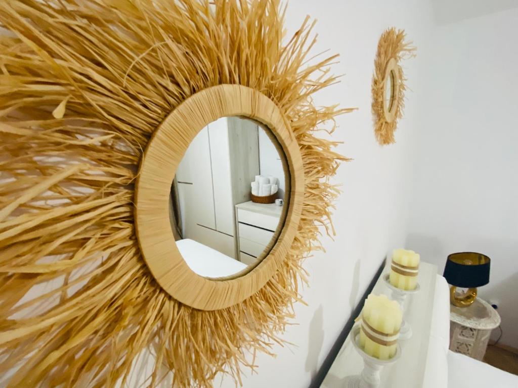 a round mirror on a wall with a straw decoration at Home away - Chic and Cozy Apartment in Constanţa