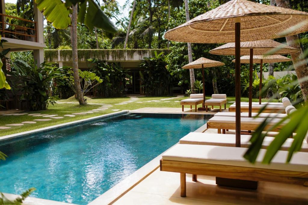 a swimming pool with lounge chairs and umbrellas at The Nook RESORT in Devinuwara