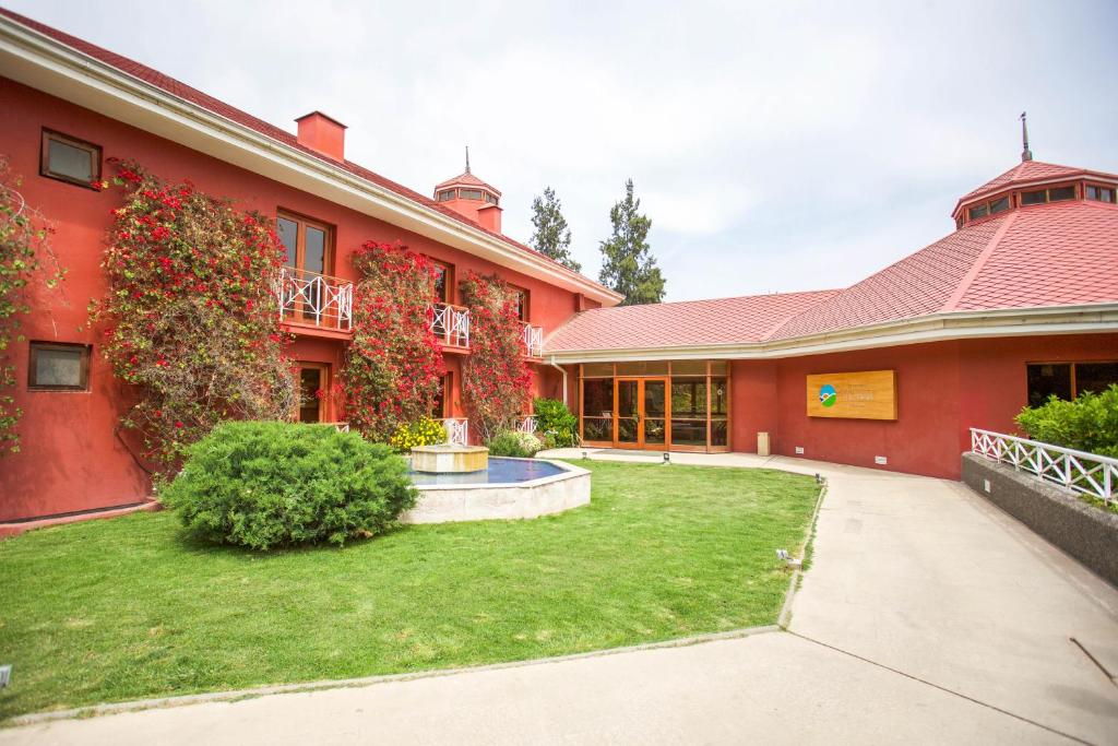 uma casa vermelha com um quintal em frente em Hotel y Cabañas Palomar - Caja los Andes em San Felipe
