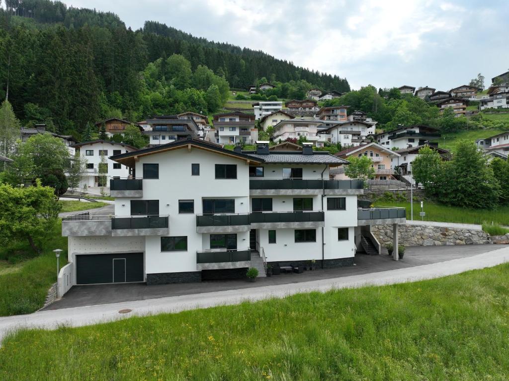ein weißes Gebäude auf einem Hügel mit Häusern in der Unterkunft Montepart Zillertal in Hainzenberg