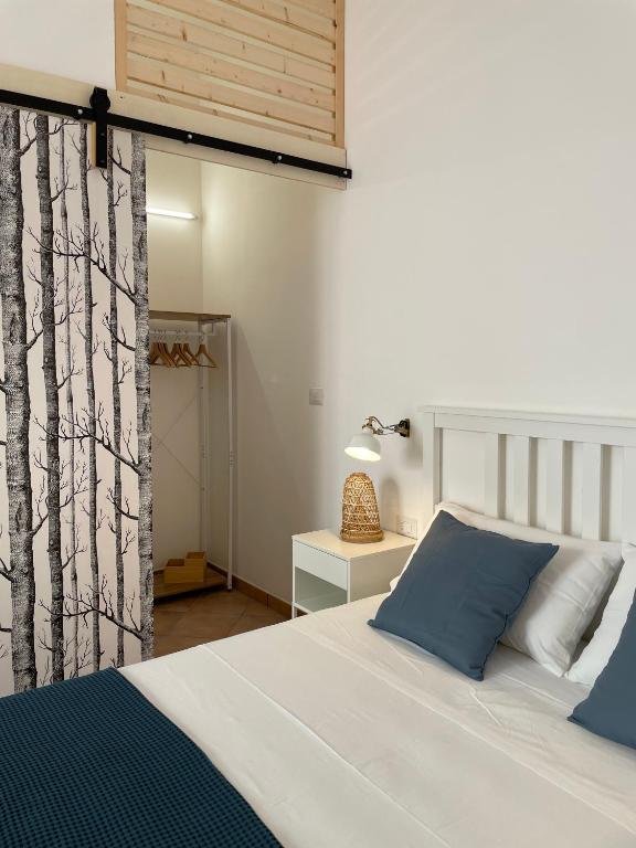 um quarto com uma cama branca e almofadas azuis em A'mmare Rooms&Apartments Santa Maria di Leuca em Leuca